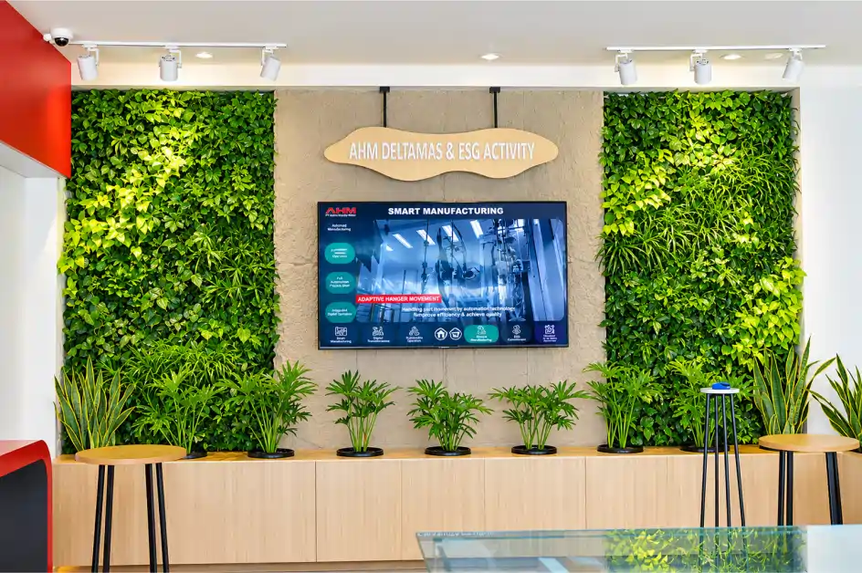 Dua panel indoor greenwall mengapit layar presentasi di ruang pamer perusahaan dengan kabinet kayu