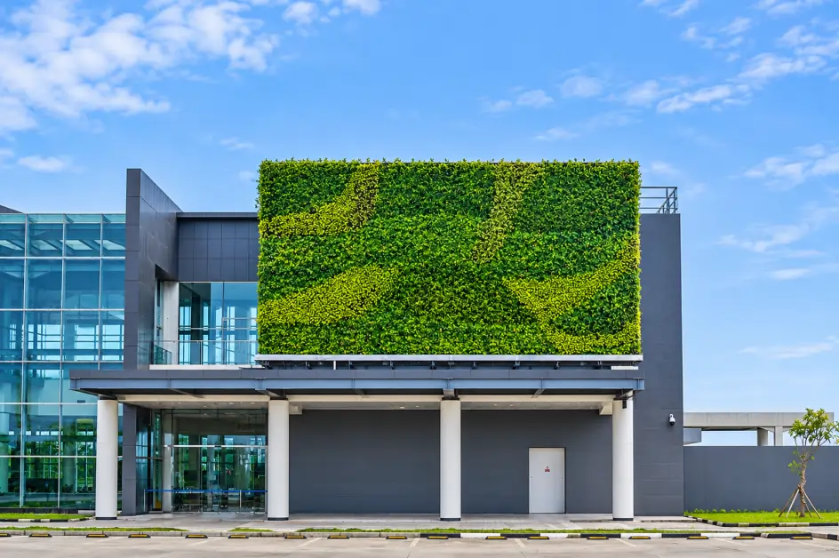 Vertical garden besar di fasad gedung modern berkaca dengan pola hijau dua tone berlatar langit biru